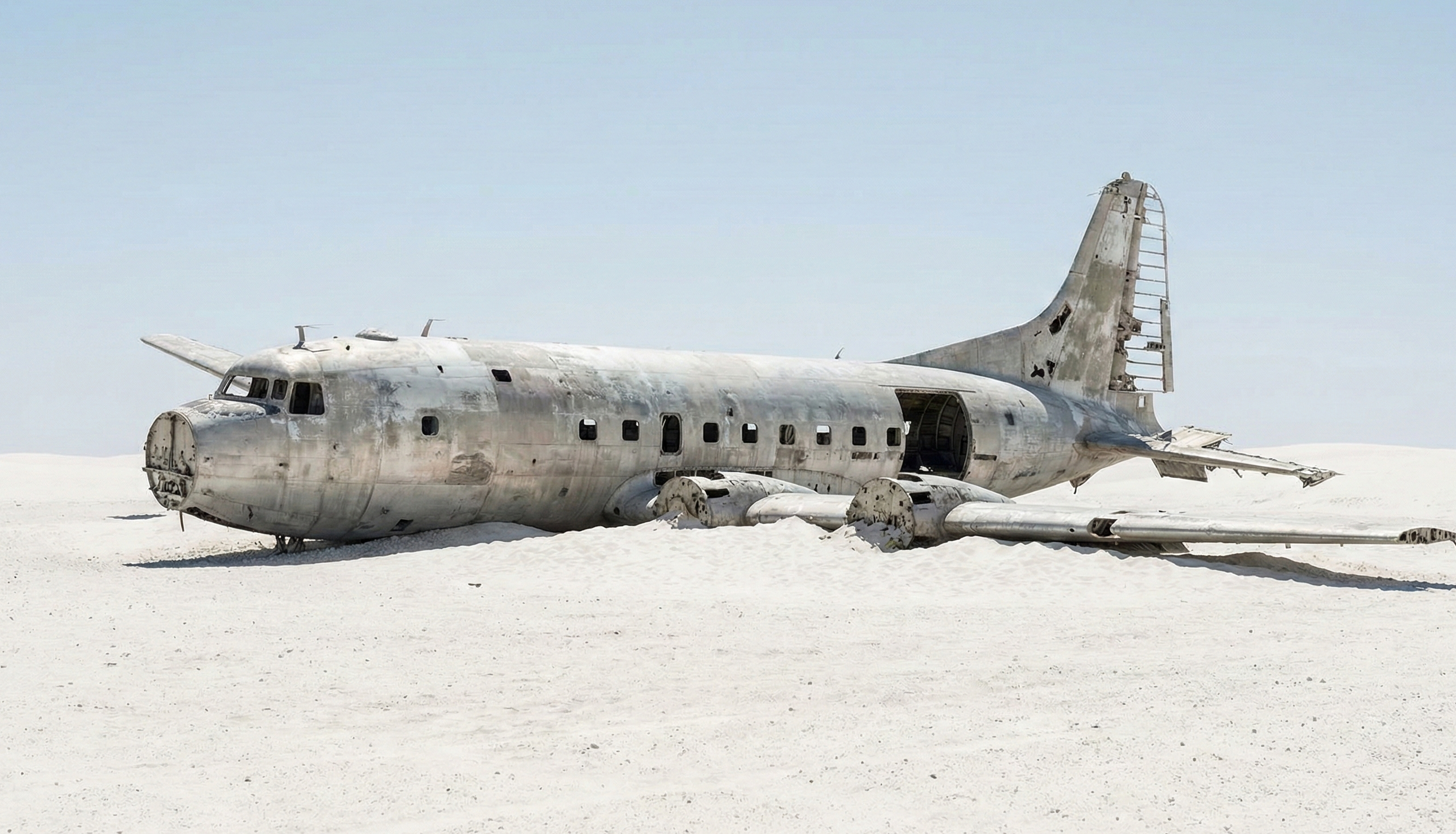 Airplane wreckage on white desert sand